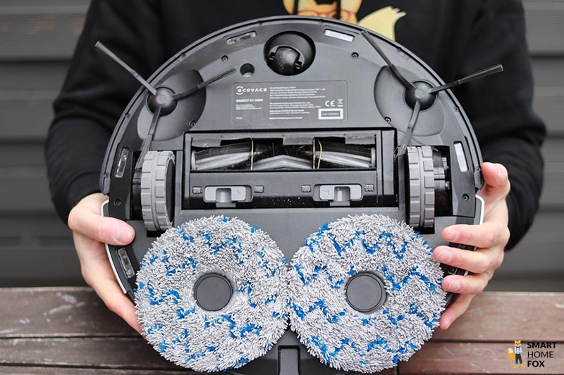 The Ecovacs Deebot X1 OMNI is held in the hands and the underside can be seen.